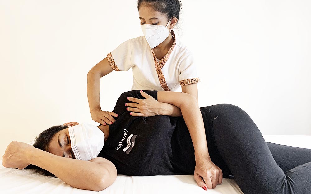 Donna e operatrice indossano la mascherina FFP2 durante il trattamento per un massaggio in piena sicurezza.