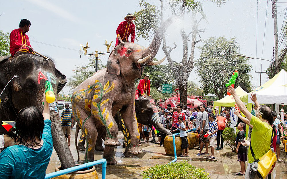 Un elefante spruzza acqua con la proboscide sulla folla durante la festa del Songkran in Thailandia.